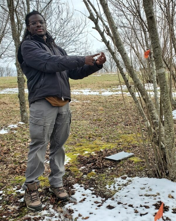Allasane Sow pointing at a tag of tree where new truffle species were found.